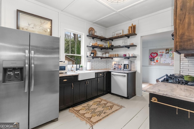 kitchen featuring a sink, open shelves, tasteful backsplash, appliances with stainless steel finishes, and dark cabinets