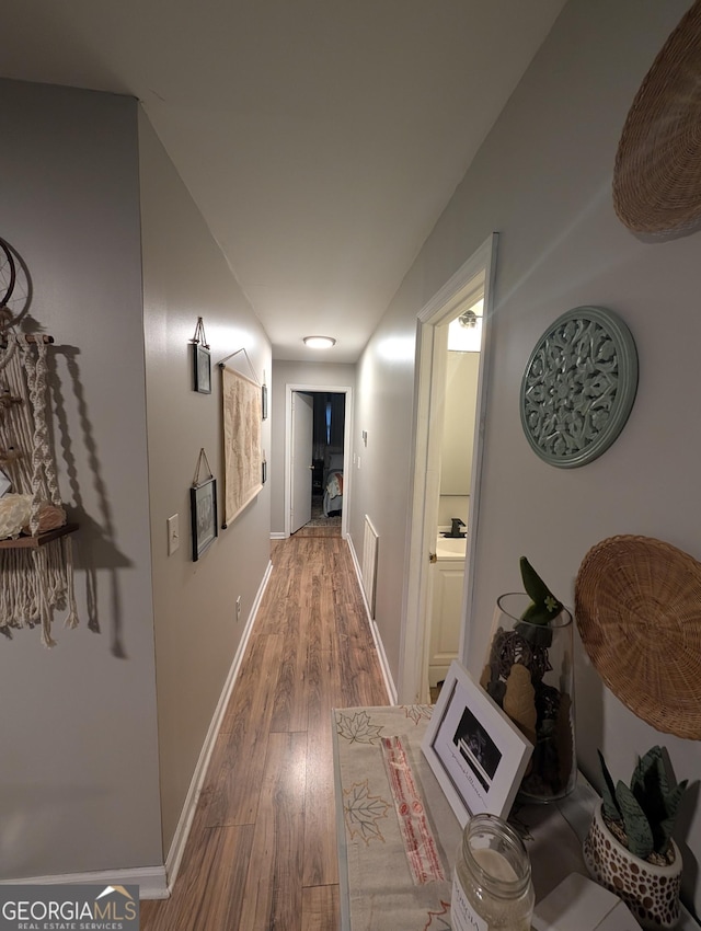 corridor featuring baseboards and wood finished floors