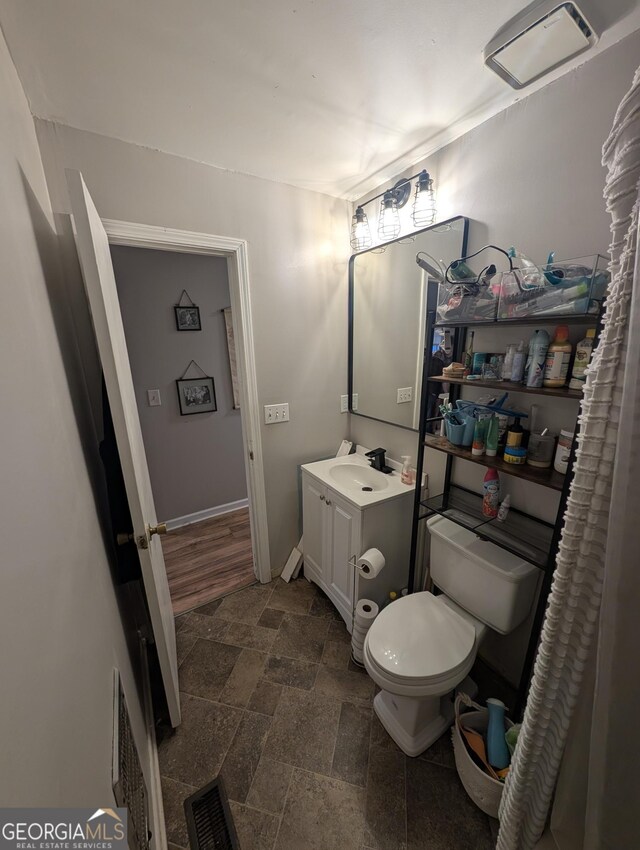 bathroom with visible vents, toilet, vanity, and stone finish flooring