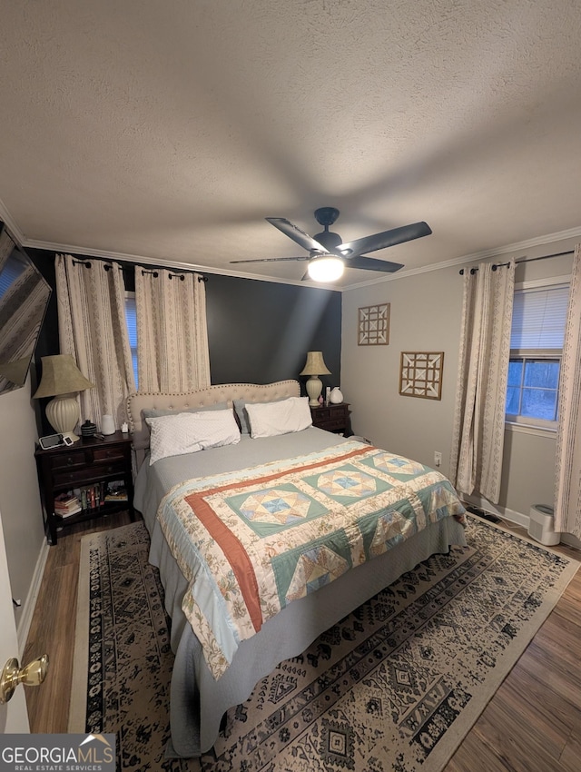 bedroom with ceiling fan, wood finished floors, baseboards, and a textured ceiling