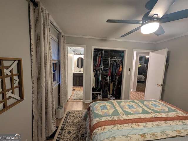 bedroom with a closet, ensuite bathroom, crown molding, and wood finished floors