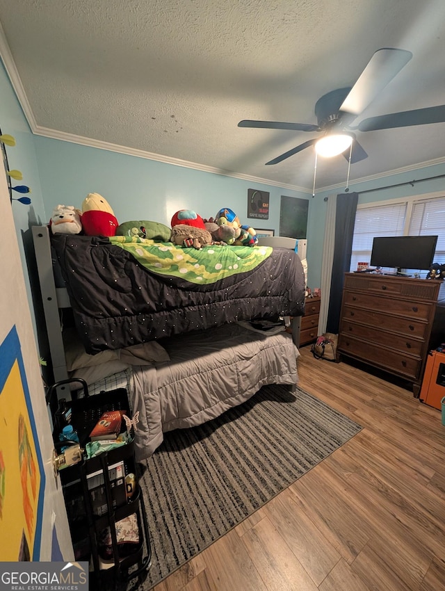 bedroom with ornamental molding, a textured ceiling, ceiling fan, and wood finished floors