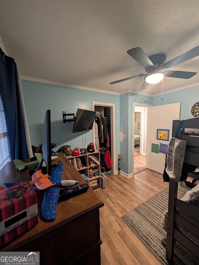 bedroom with baseboards, ceiling fan, ornamental molding, wood finished floors, and a textured ceiling