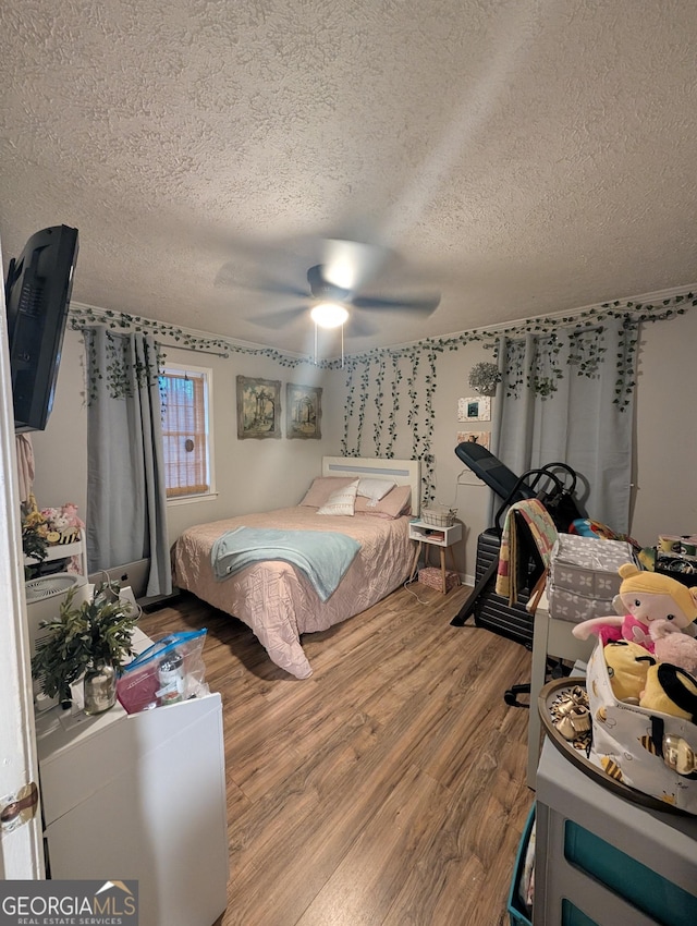 bedroom with a textured ceiling, ceiling fan, and wood finished floors