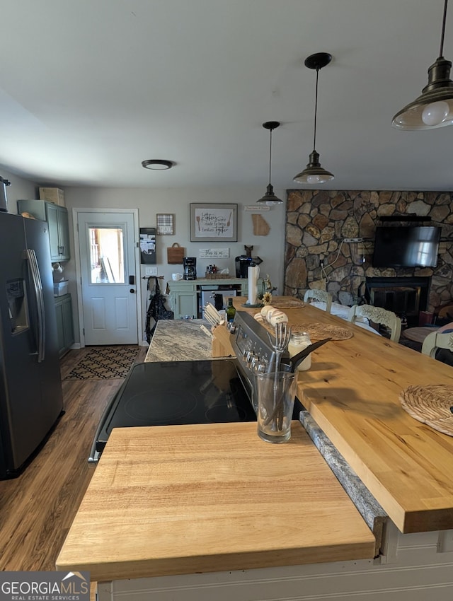 kitchen with dark wood finished floors, hanging light fixtures, electric stove, and fridge with ice dispenser