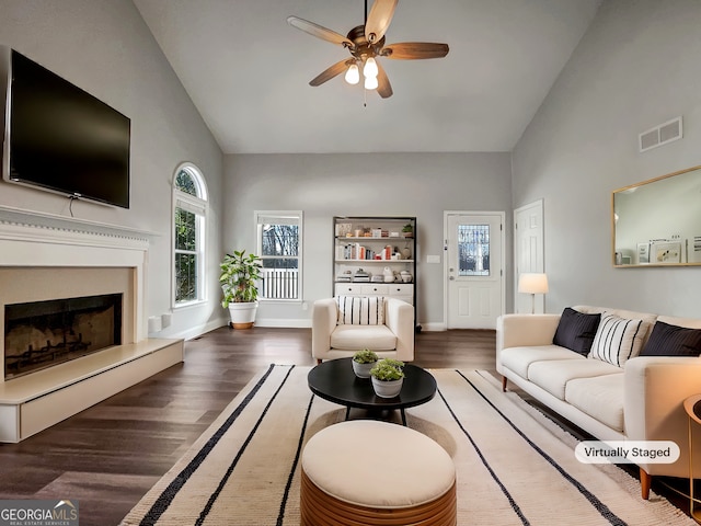 living room featuring visible vents, high vaulted ceiling, a fireplace with raised hearth, and wood finished floors