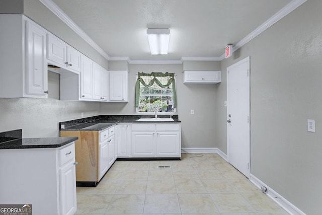 kitchen with visible vents, crown molding, light tile patterned floors, white cabinetry, and a sink