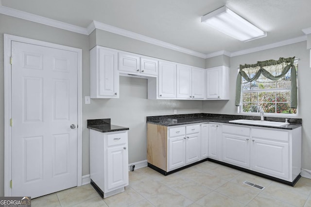 kitchen with white cabinets, ornamental molding, and a sink