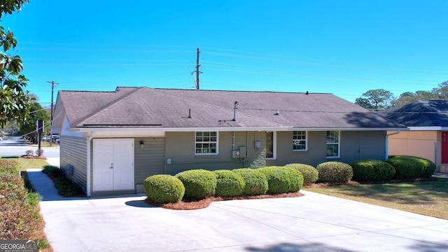 ranch-style home with roof with shingles and concrete driveway