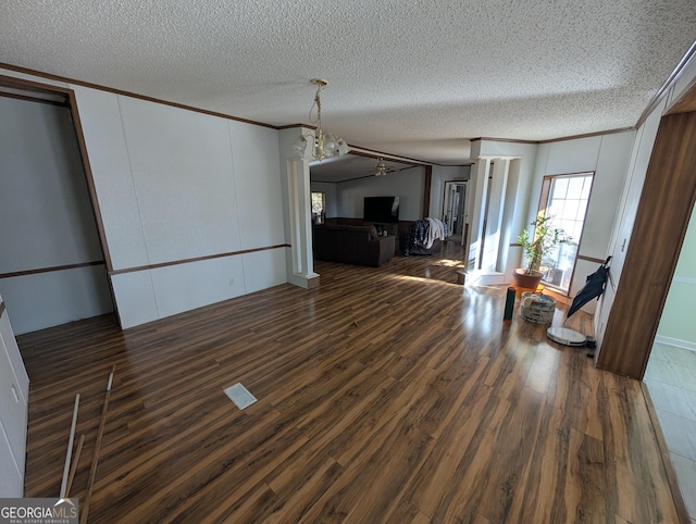 unfurnished living room with a textured ceiling, wood finished floors, and ornamental molding