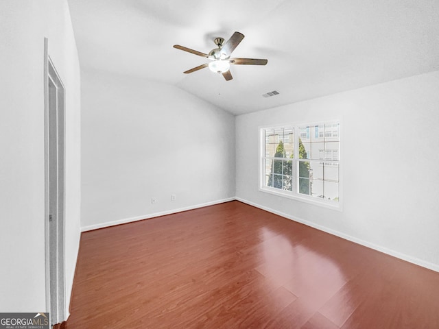 unfurnished room featuring baseboards, visible vents, dark wood finished floors, lofted ceiling, and ceiling fan