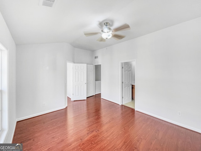 empty room with baseboards, wood finished floors, visible vents, and ceiling fan