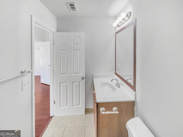 half bathroom featuring tile patterned flooring, toilet, vanity, and visible vents