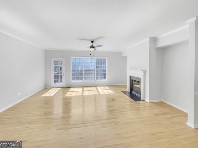 unfurnished living room with a fireplace with flush hearth, crown molding, light wood-type flooring, and baseboards