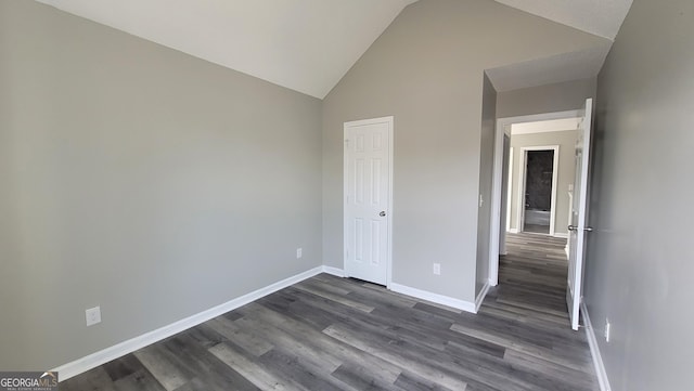 unfurnished bedroom featuring dark wood-type flooring, baseboards, a closet, and high vaulted ceiling