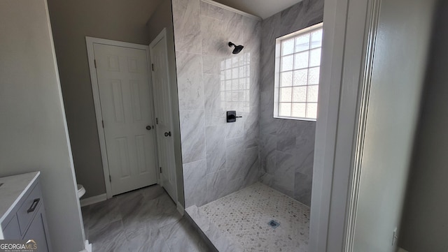 full bathroom with baseboards, toilet, tiled shower, marble finish floor, and vanity