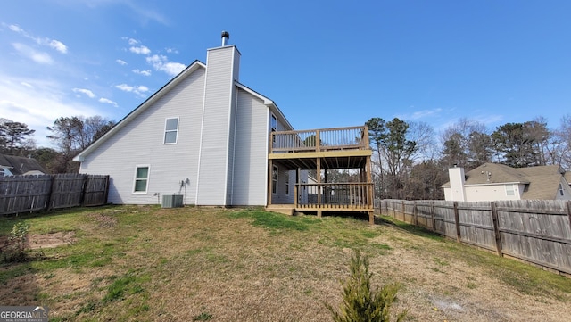 back of house with a wooden deck, a lawn, a fenced backyard, and a chimney