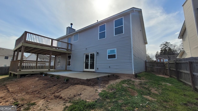 rear view of house featuring a fenced backyard, a chimney, a wooden deck, and a patio