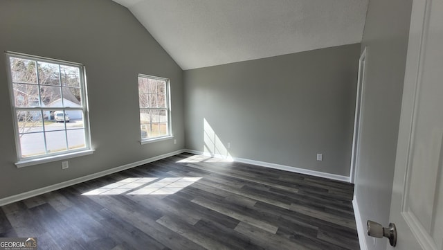 unfurnished room featuring dark wood-style floors, a textured ceiling, baseboards, and lofted ceiling