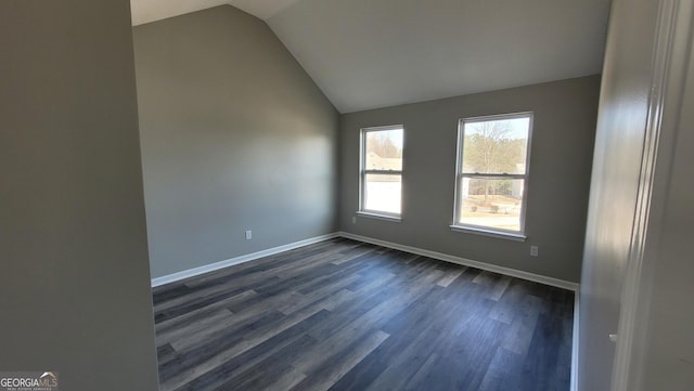 spare room featuring dark wood finished floors, lofted ceiling, and baseboards