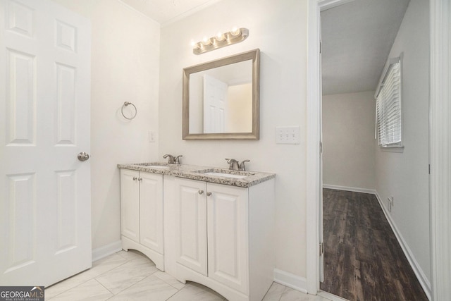 bathroom with double vanity, marble finish floor, baseboards, and a sink