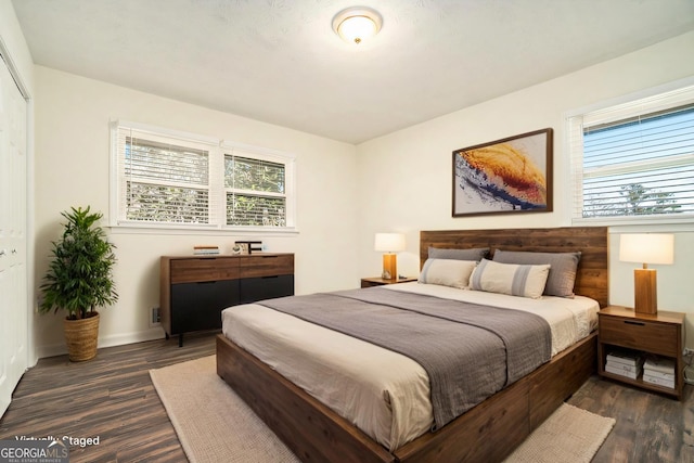 bedroom with baseboards and dark wood-type flooring