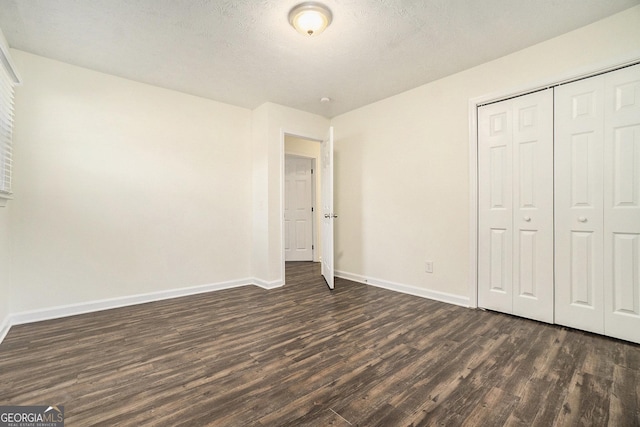 unfurnished bedroom featuring a closet, dark wood-type flooring, and baseboards