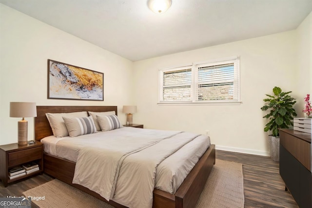 bedroom with dark wood finished floors and baseboards