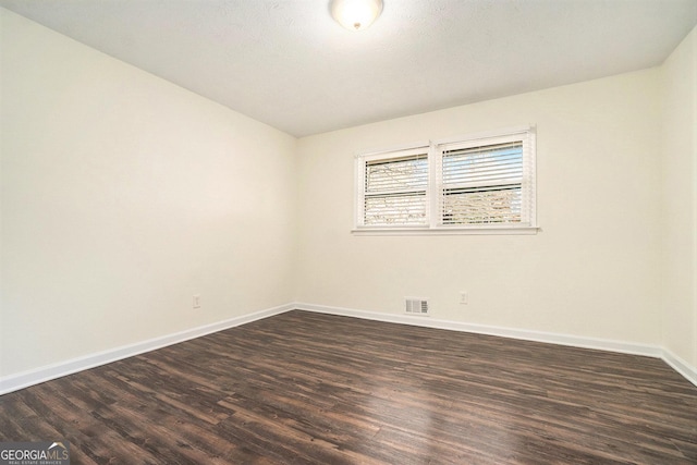 empty room with dark wood-type flooring, baseboards, and visible vents