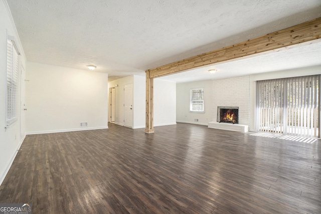 unfurnished living room featuring a brick fireplace, a textured ceiling, and wood finished floors