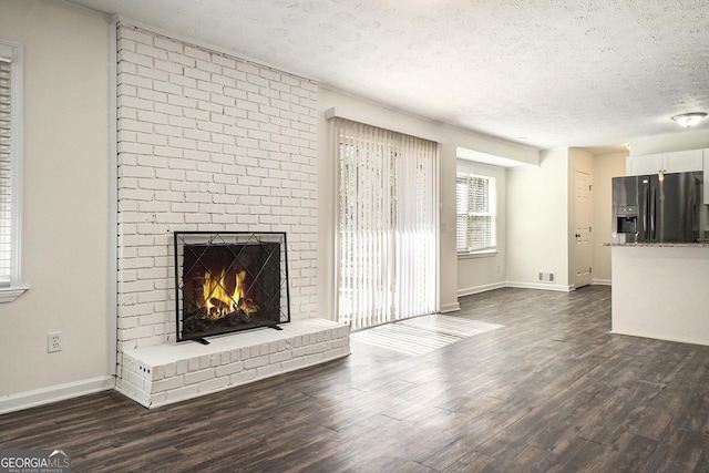 unfurnished living room featuring visible vents, dark wood-type flooring, a textured ceiling, and a fireplace