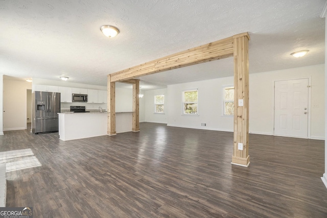 unfurnished living room featuring dark wood-style floors, baseboards, and a textured ceiling