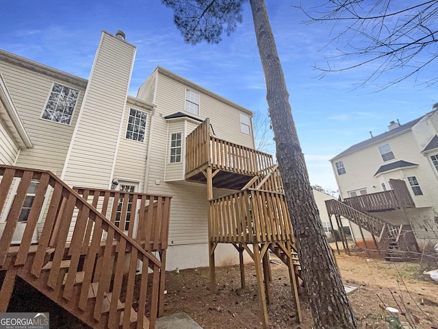 rear view of property with stairs, a deck, and a chimney