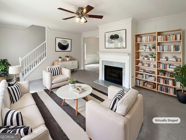 living room featuring stairs, ceiling fan, a high end fireplace, and ornamental molding