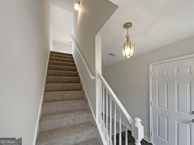 stairs with visible vents and a textured ceiling