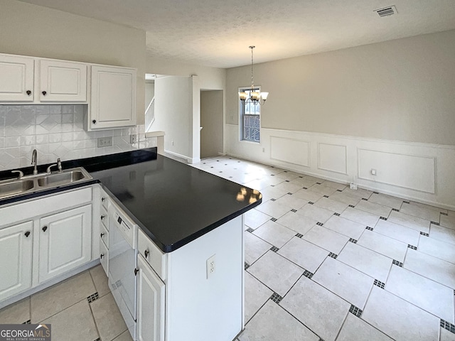 kitchen with visible vents, a sink, dark countertops, a peninsula, and dishwasher