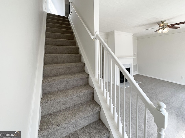 stairway with carpet flooring, a fireplace, baseboards, and ceiling fan