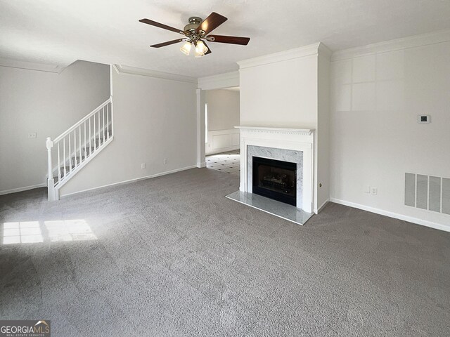 unfurnished living room with visible vents, ornamental molding, a high end fireplace, carpet flooring, and stairs