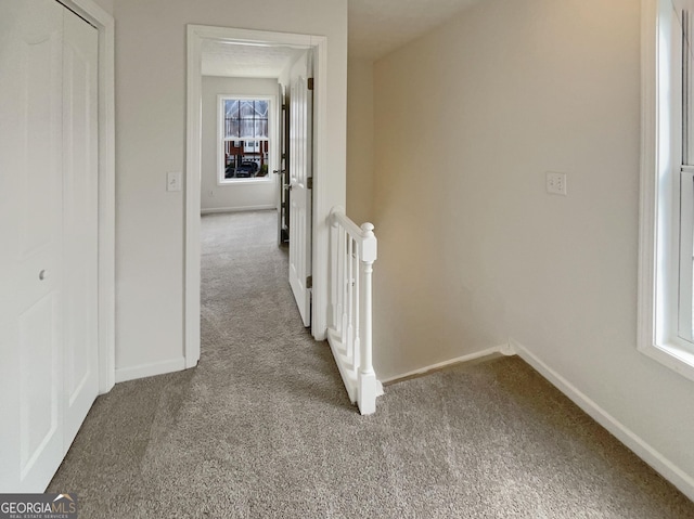 hallway with baseboards, carpet floors, and an upstairs landing