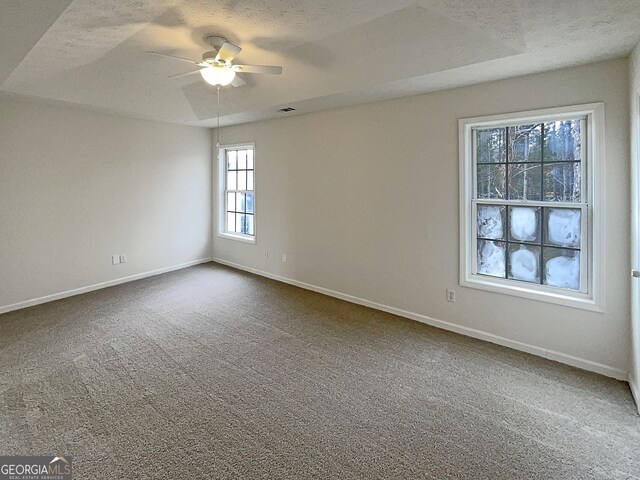 spare room with dark colored carpet, baseboards, a textured ceiling, and ceiling fan