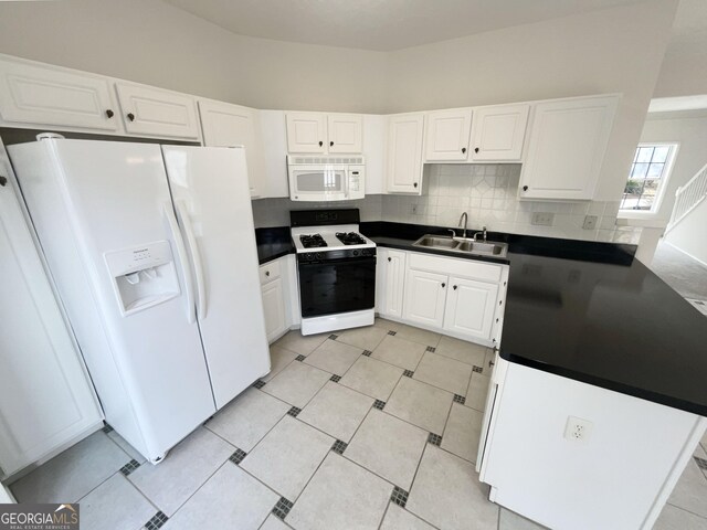 kitchen featuring white appliances, white cabinets, dark countertops, and a sink