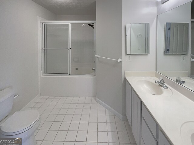 bathroom with toilet, double vanity, tile patterned floors, a textured ceiling, and a sink