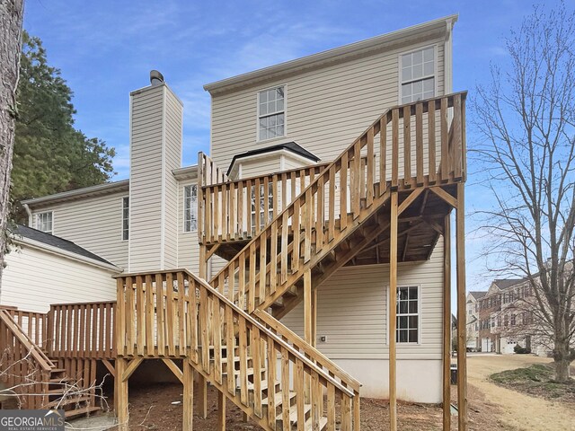 rear view of property with stairway and a deck