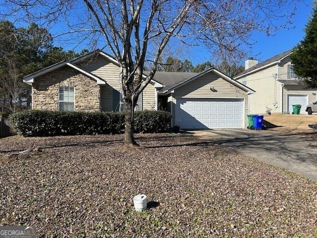 ranch-style house with stone siding, concrete driveway, and an attached garage