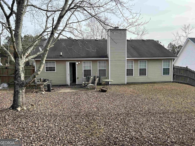 rear view of property with fence and a chimney