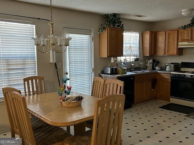 kitchen featuring under cabinet range hood, black dishwasher, white range with gas cooktop, a notable chandelier, and a sink