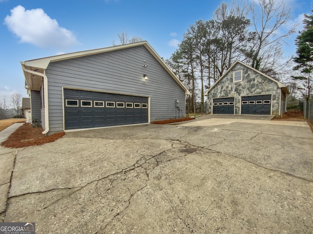 view of side of home with stone siding, a detached garage, and an outdoor structure