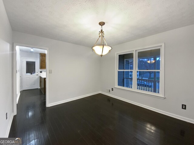 unfurnished dining area featuring dark wood finished floors, visible vents, baseboards, and a textured ceiling