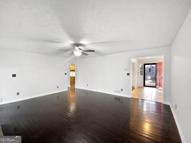 unfurnished living room with visible vents, a textured ceiling, baseboards, and hardwood / wood-style floors