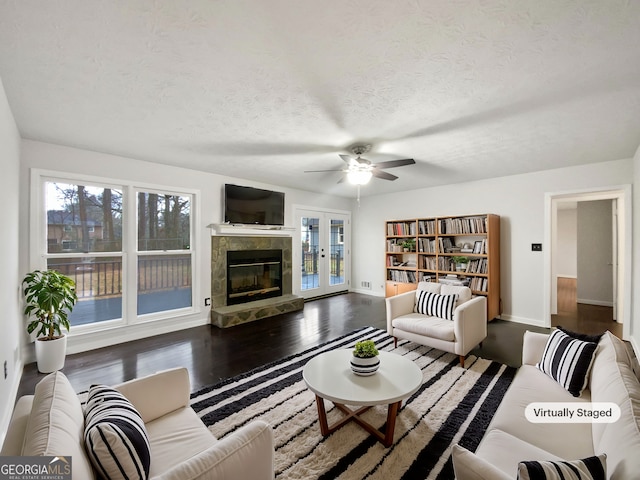 living area with a tiled fireplace, wood finished floors, a healthy amount of sunlight, and a textured ceiling